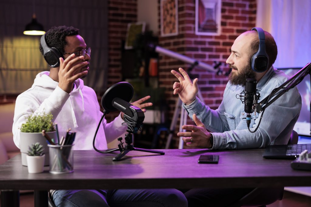 Duas pessoas gravando episódio com microfones e fones de ouvido em um estúdio, representando a produção e monetização de podcast.